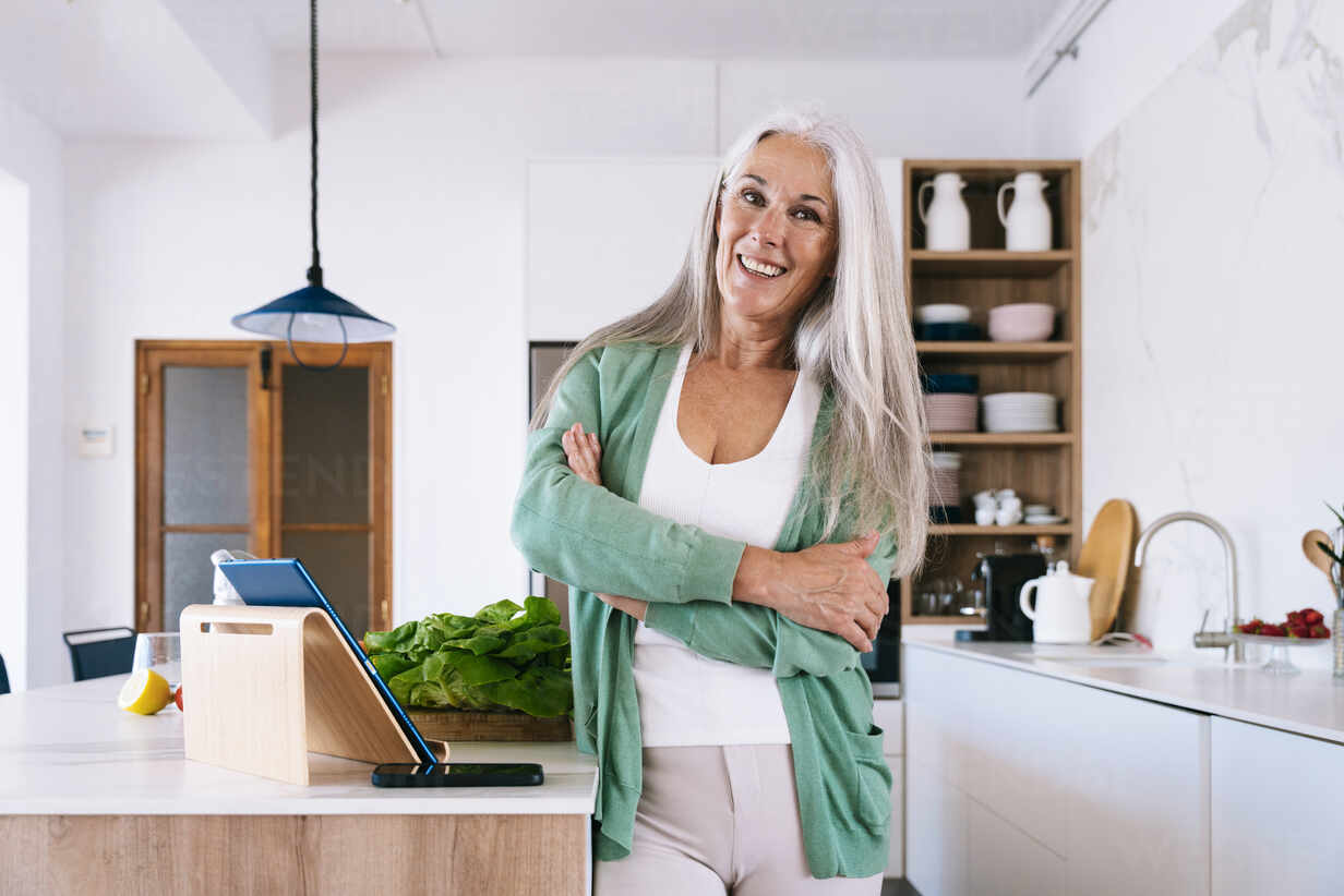 Glückliche Reife Frau Steht Mit Verschränkten Armen In Der Küche Zu Hause Lizenzfreies Stockfoto 2308